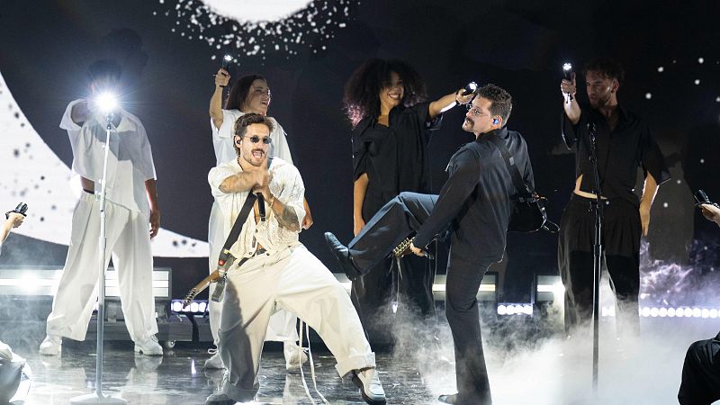 Mau y Ricky en Premios Juventud 2026: Mau de blanco canta con pasión, Ricky de negro lo sostiene. Escenario con luces, humo y bailarines.