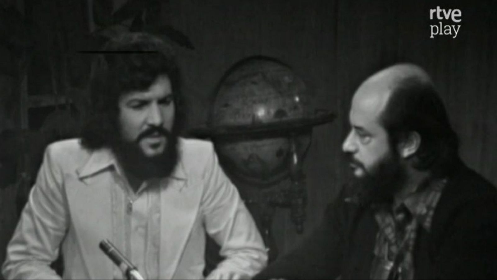 Dr. Fernando Jiménez del Oso e Iván Trilha en "Más allá" de RTVE. Fotograma en blanco y negro con globo terráqueo de fondo.