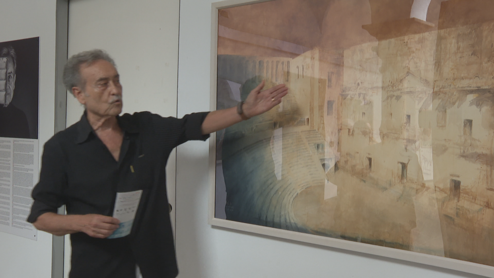 Antonio López García señala una obra arquitectónica en una galería. A su izquierda, una imagen en blanco y negro de un rostro enmascarado con texto debajo.