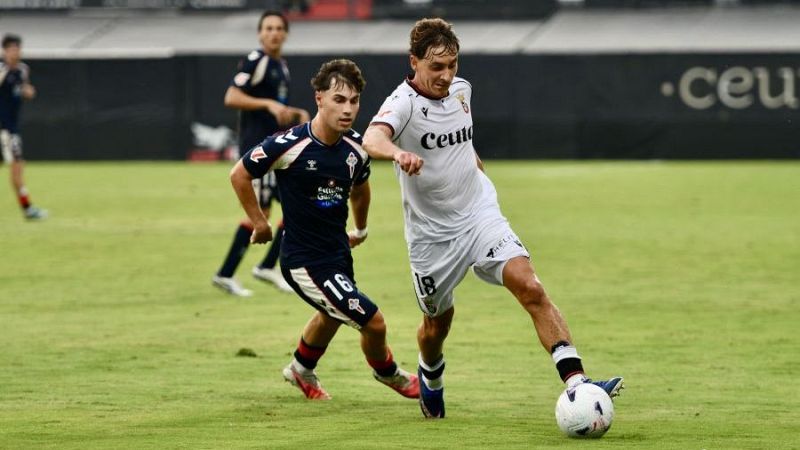 Jugador del CEUTA (dorsal 18, camiseta blanca) dribla bal�n ante jugador del Celta B (dorsal 16, camiseta azul oscura) en partido de f�tbol.