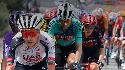 Ciclistas en plena carrera, Tadej Poga?ar con maillot UAE Emirates, otro con Kern Pharma y uno m�s con Tudor Pro Cycling Team. D�a soleado, enfoque en el esfuerzo.