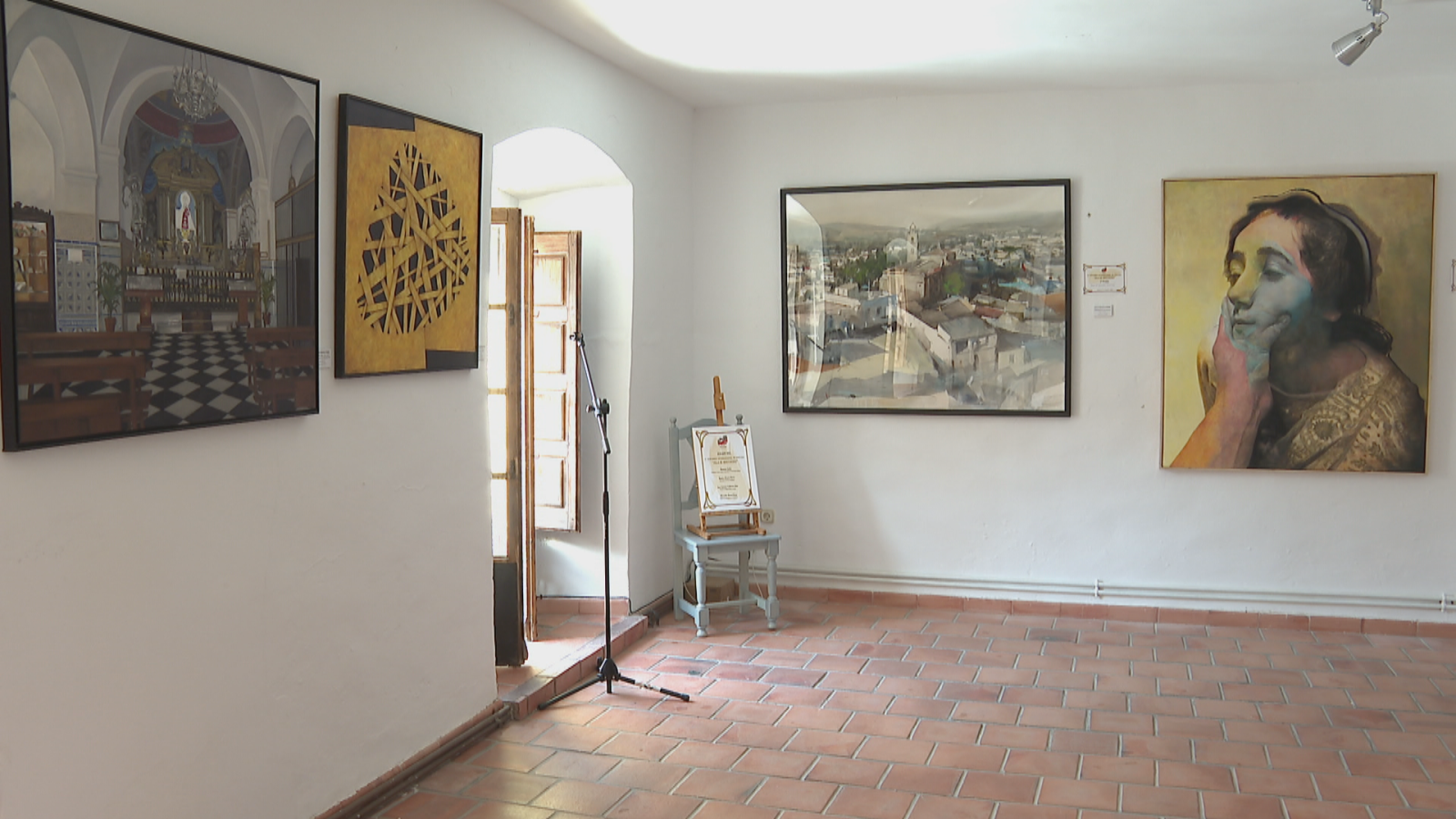 Galería de arte con obras diversas: paisaje, retrato vibrante, iglesia y un certificado de "PREMIO".