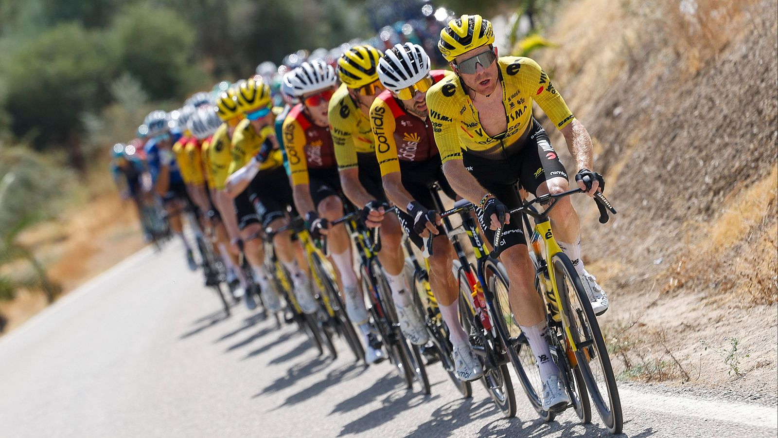 Jonas Vingegaard (Visma | Lease a Bike) lidera una carrera ciclista, seguido de cerca por un corredor de Cofidis. La escena muestra esfuerzo y competición bajo un sol radiante.