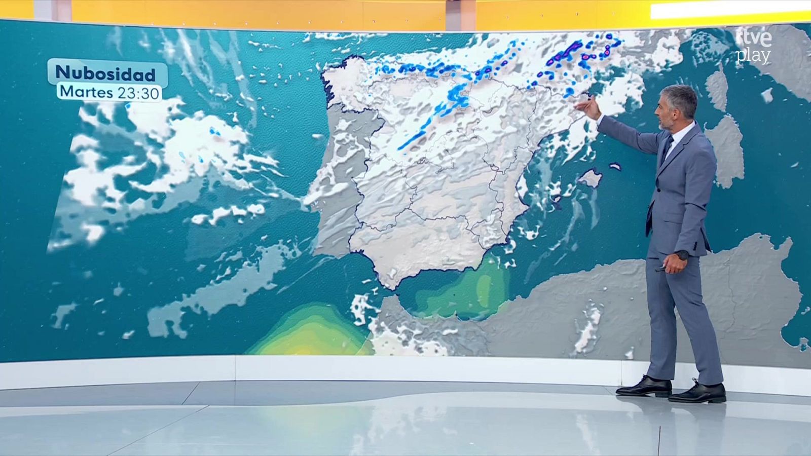 Martín Barreiro, en un estudio de TVE, presenta el pronóstico del tiempo señalando un mapa detallado de la Península Ibérica con nubosidad y precipitaciones.