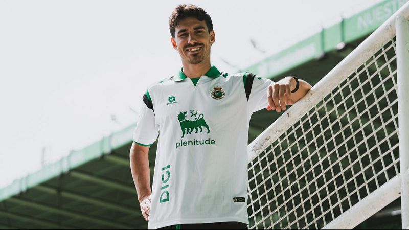 Íñigo Vicente, jugador del Racing de Santander, sonríe a cámara con la equipación del equipo, luciendo logos de Givova, Eni (plenitude) y DIGI. Fondo de estadio.