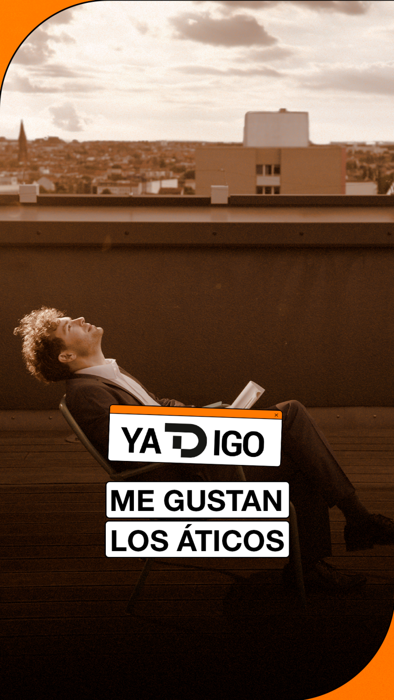 Joven en terraza con vista urbana, sostiene objeto blanco. "YA DIGO" y "ME GUSTAN LOS ÁTICOS" superpuestos. Filtro cálido.