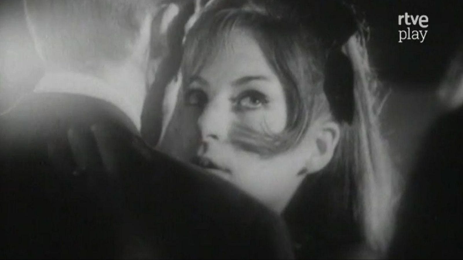 Primer plano en blanco y negro de una mujer joven bailando, con mirada intensa. Se distingue el logo de "rtve play".