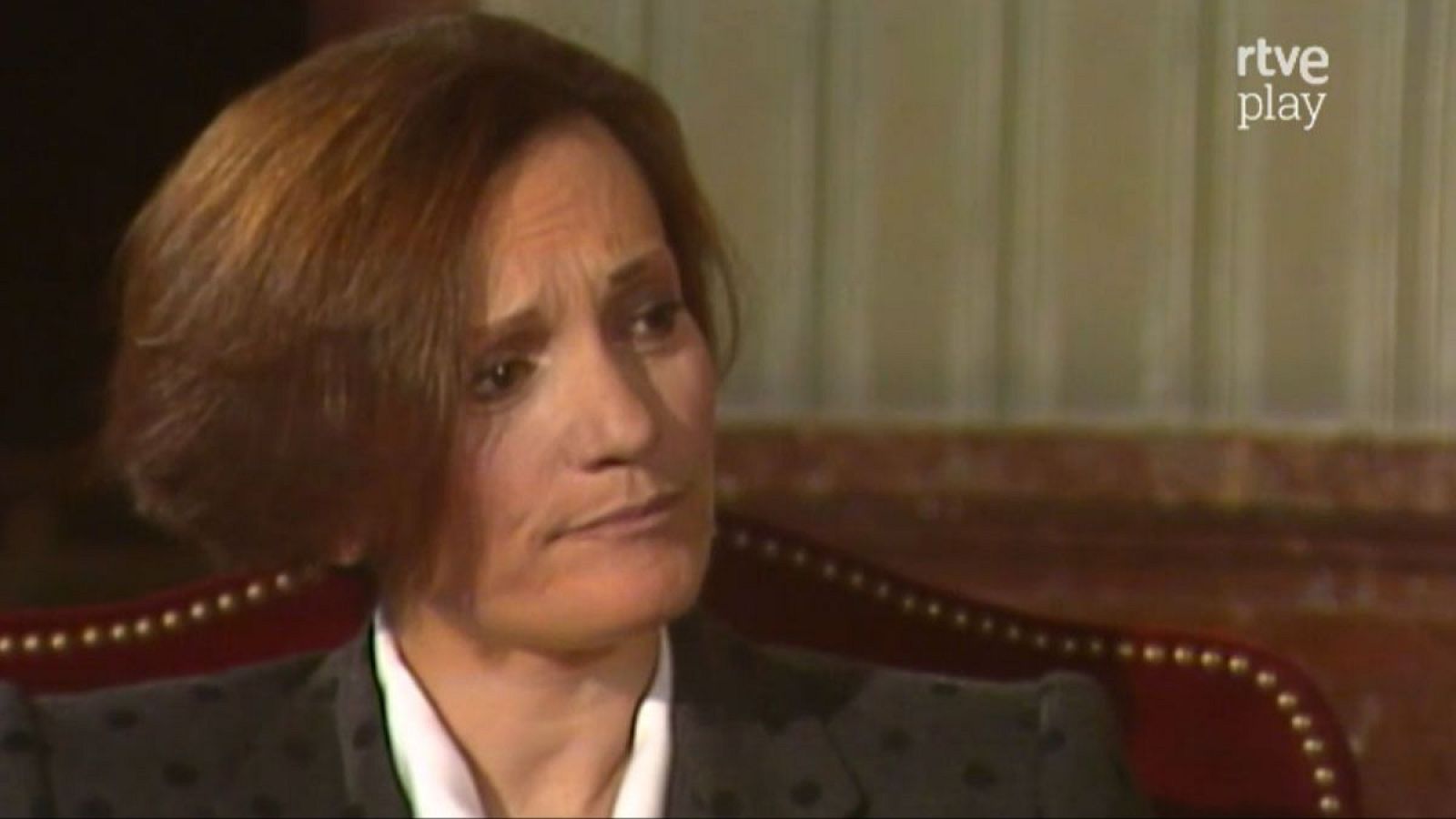 Pilar Miró, directora española, con expresión seria, vestida con chaqueta oscura y blusa blanca, sentada en sillón clásico. Logo "rtve play" visible.
