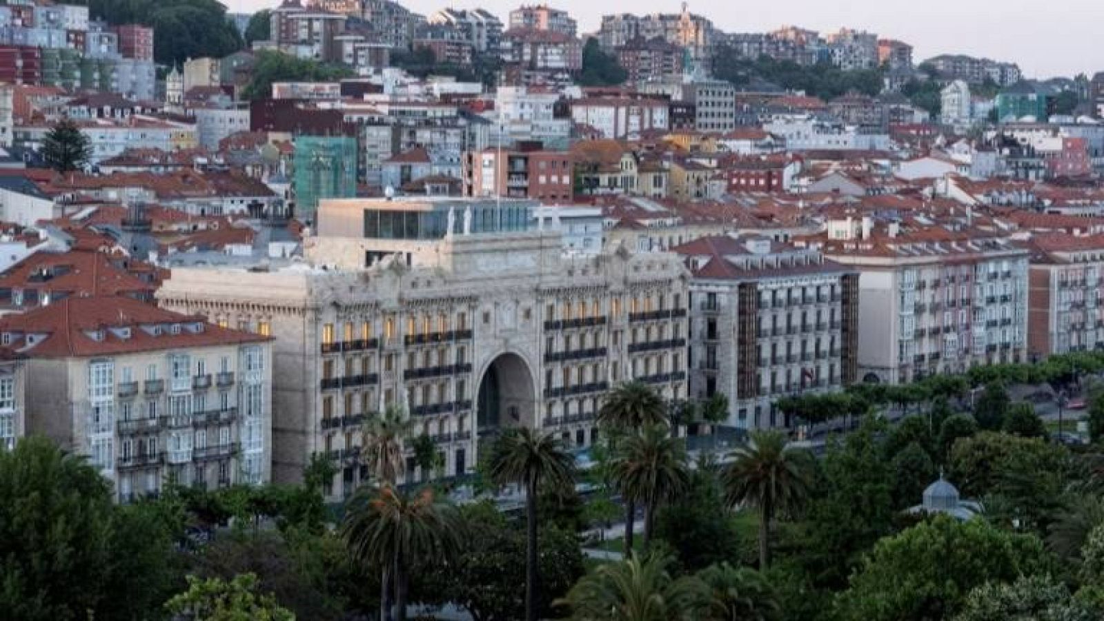 Vista panorámica del Faro Santander, un edificio clásico con un gran arco, rodeado de vegetación y la ciudad al fondo.