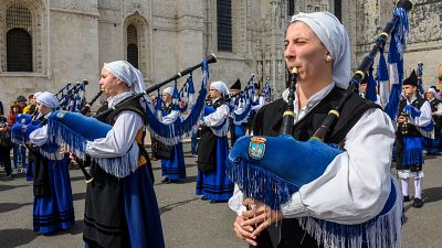 Mujer tocando una gaita azul con el escudo de Oviedo, rodeada por la Real Banda de Gaitas 'Ciudad de Oviedo' frente al Monasterio de los Jer�nimos en Lisboa.
