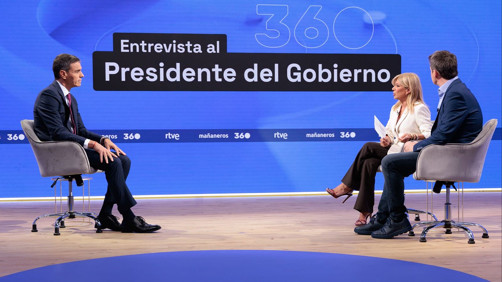 Pedro Sánchez, Presidente del Gobierno, es entrevistado en un estudio de televisión. Le acompañan una mujer y un hombre, todos sentados en sillas de oficina.