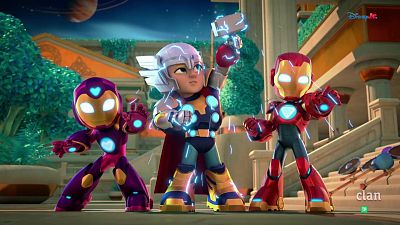 Tres superhéroes infantiles, Thor, Iron Man y uno de armadura púrpura, en poses de acción con energía luminosa. Fondo arquitectónico, cielo nocturno con planeta anillado. Logotipos "Disney Jr." y "clan" visibles.