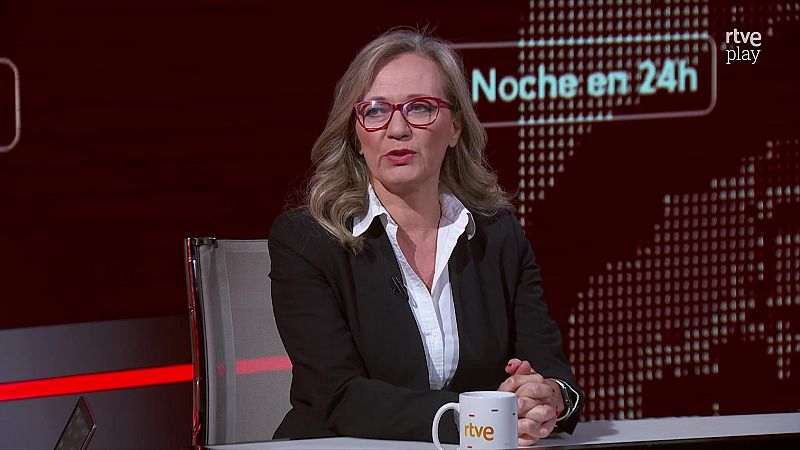 Silvia Intxaurrondo, con gafas rojas y blazer negro, en el estudio de "Noche en 24h" de rtve play. Fondo granate, taza de rtve.