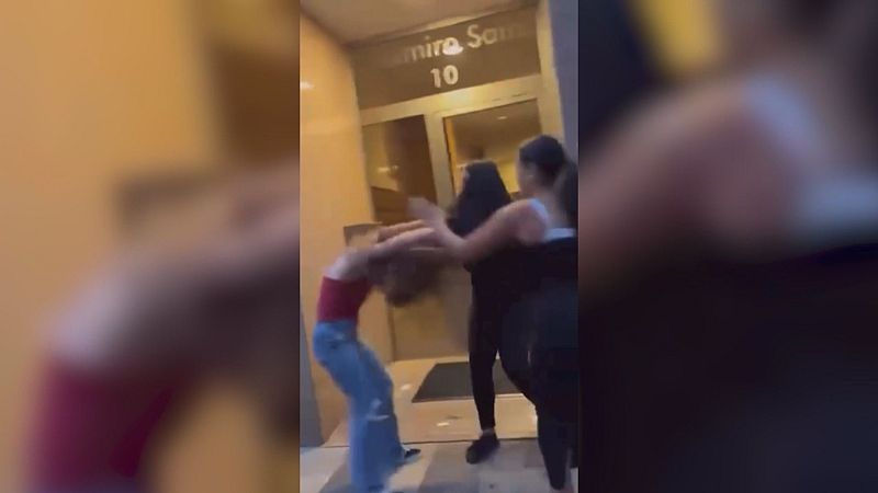 Tres mujeres en una agresión nocturna frente a un edificio con el número 10 y el texto "mire Sa". Una de ellas, de rojo, se defiende de las otras dos.