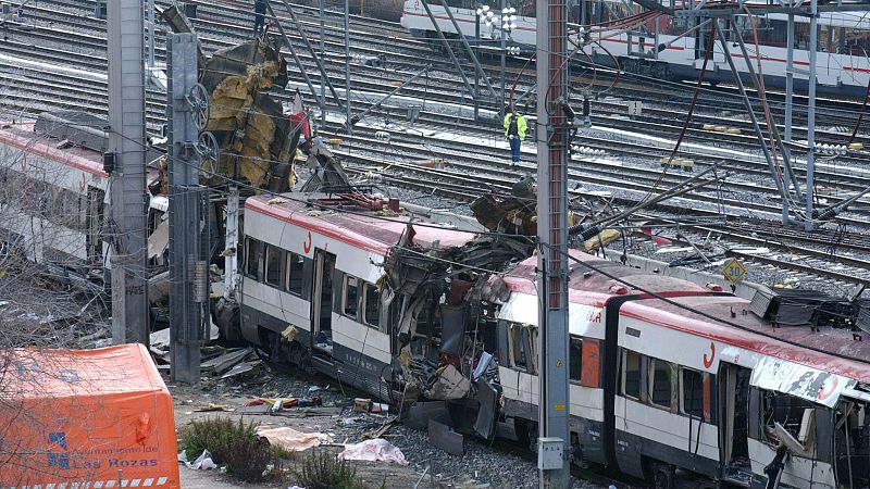 Vista aérea de un devastador accidente ferroviario de Renfe con vagones destrozados, vías afectadas y personal de emergencia en la zona. Se distingue una lona del Ayuntamiento de Las Rozas.