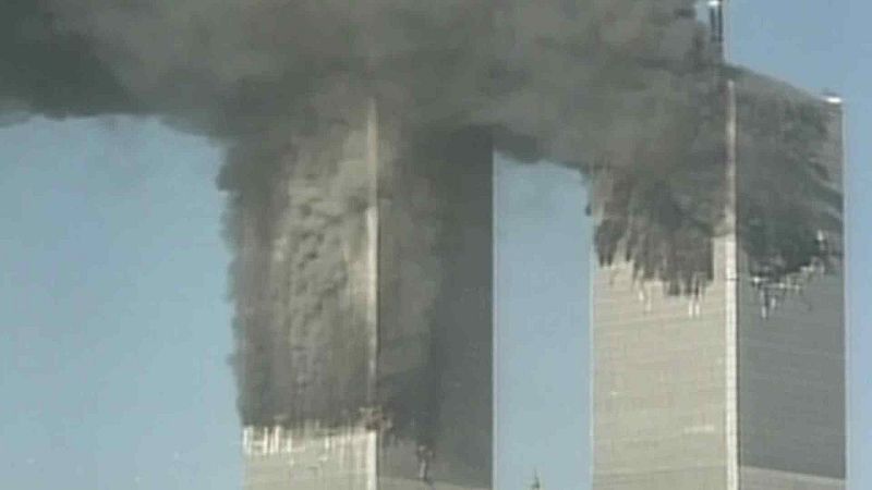 Las Torres Gemelas del World Trade Center en Nueva York emiten humo denso y oscuro tras los ataques del 11 de septiembre de 2001. Se observa daño estructural significativo en medio de un cielo azul.