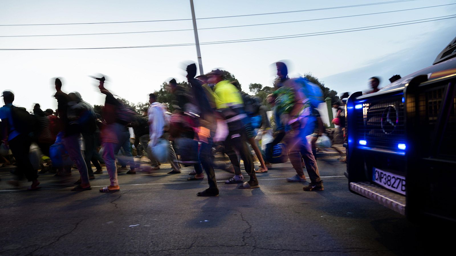 Centenares de personas se trasladan a pie durante el dispositivo de reubicación de migrantes hasta un nuevo centro temporal, en el barrio de Los Rosales