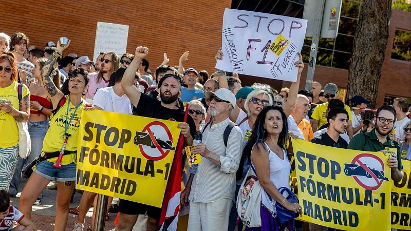 Manifestantes protestan contra la Fórmula 1 en Madrid con pancartas y consignas. Se observa una gran pancarta amarilla con "STOP FÓRMULA-1 MADRID" y un símbolo de prohibición de F1. Varias personas alzan el puño.