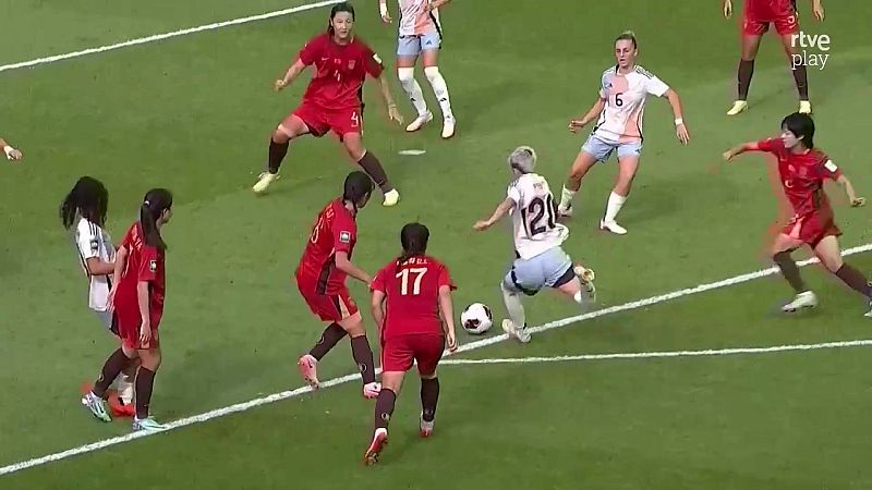 Jugadora n�mero 12 de blanco y azul claro disputa el bal�n a jugadoras de rojo en un partido de f�tbol. Se ve el logo "rtve play".