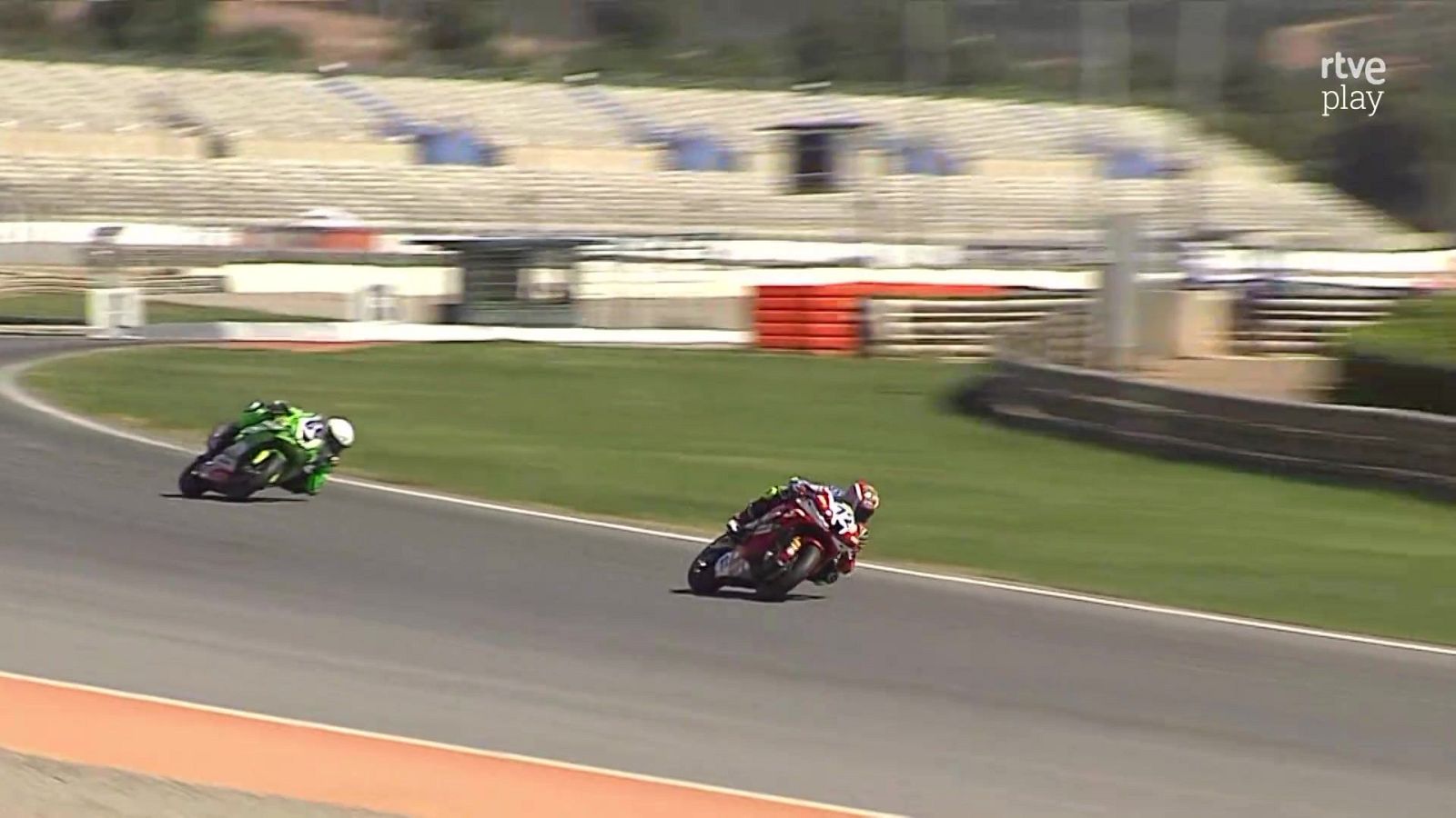 Dos motociclistas, con los números 2 y 21, compiten en una curva cerrada. El logo "rtve play" aparece en la esquina superior derecha.