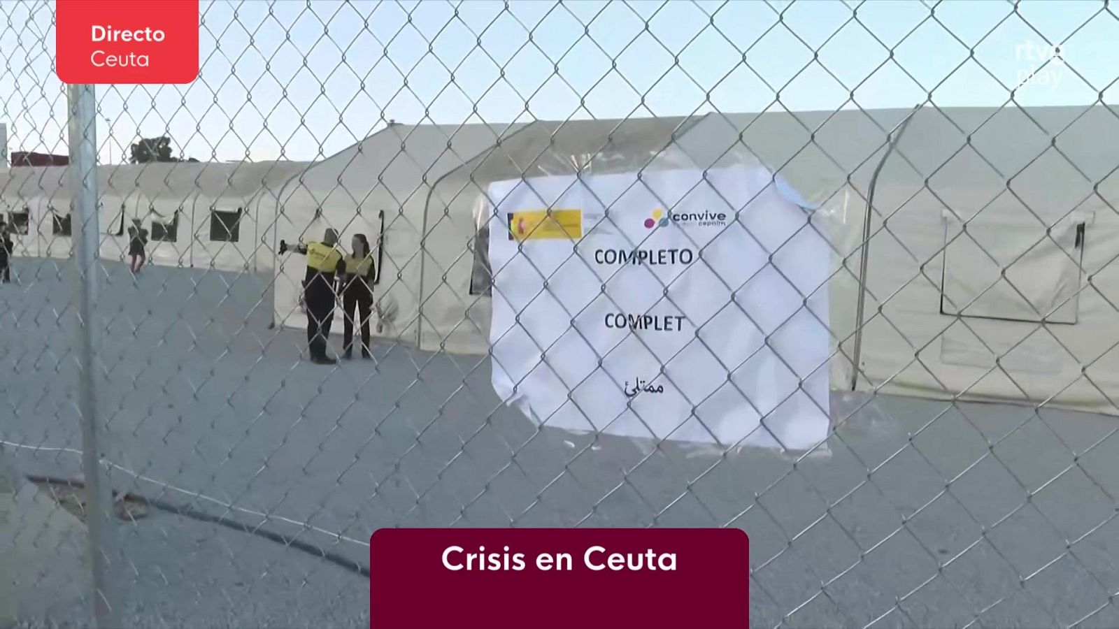 Centro de acogida en Ceuta "COMPLETO" con personal de seguridad y tiendas de campaña, en el contexto de una crisis.