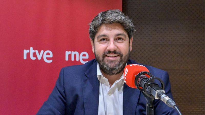 Primer plano de Íñigo Alfonso, presentador de "Las mañanas de RNE", sonriendo con barba canosa y chaqueta azul marino. Fondo rojo con logos "rtve" y "rne".