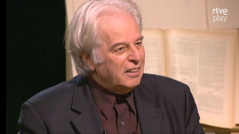 Alejandro Jodorowsky, hombre de cabello blanco y ojos oscuros, viste chaqueta oscura y camisa granate. Boca entreabierta, expresión atenta. Fondo con libro y logo 'rtve play'.