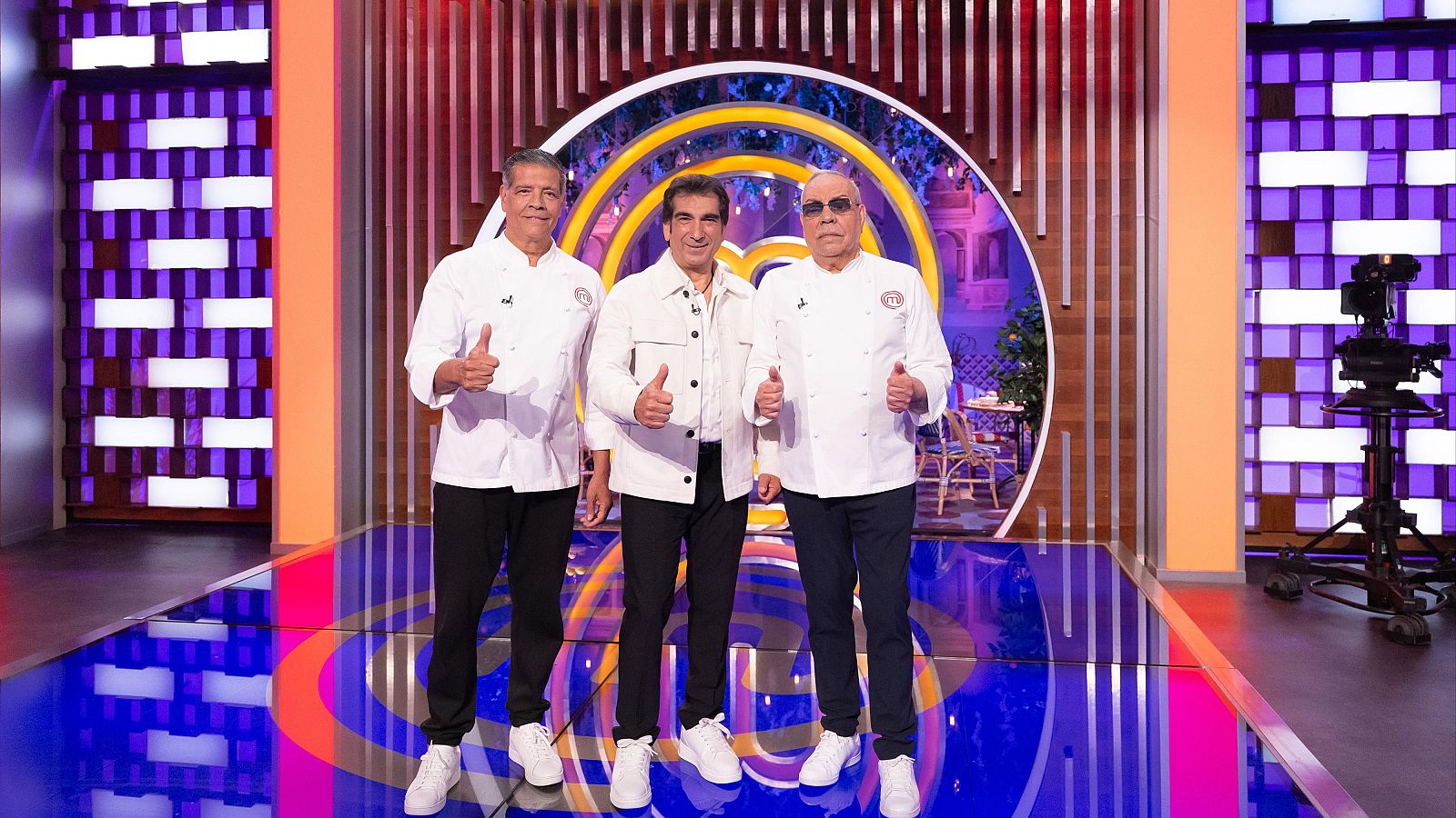 Juan Salazar, José Salazar y un tercer hombre calvo con gafas de sol, vestidos de chef, posan sonrientes con pulgares arriba en el plató de MasterChef Celebrity Legends.