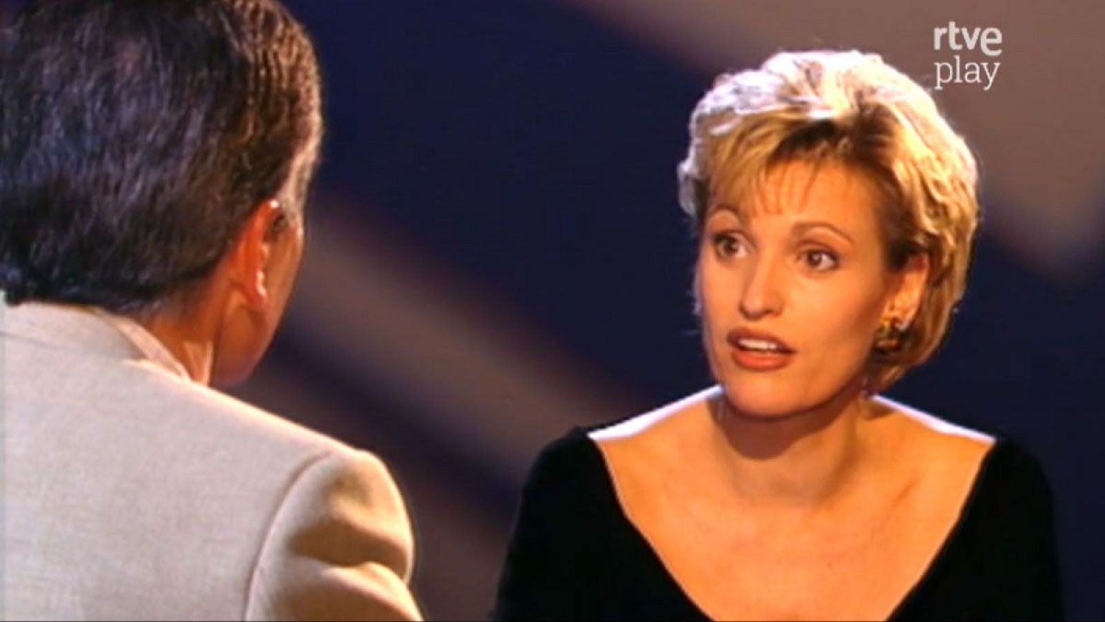 Ainhoa Arteta y Pedro Ruiz en "La noche abierta" de RTVE. Ella, de frente, con pelo rubio y pendientes dorados; él, de espaldas, con chaqueta clara. Logo "rtve play" visible.