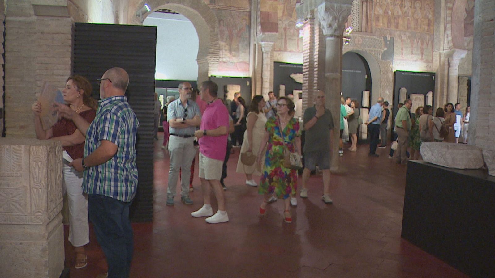 Visitantes disfrutan de las "Noches del Patrimonio" en un edificio histórico con arquitectura de arcos y columnas, observando exposiciones y la estructura antigua.