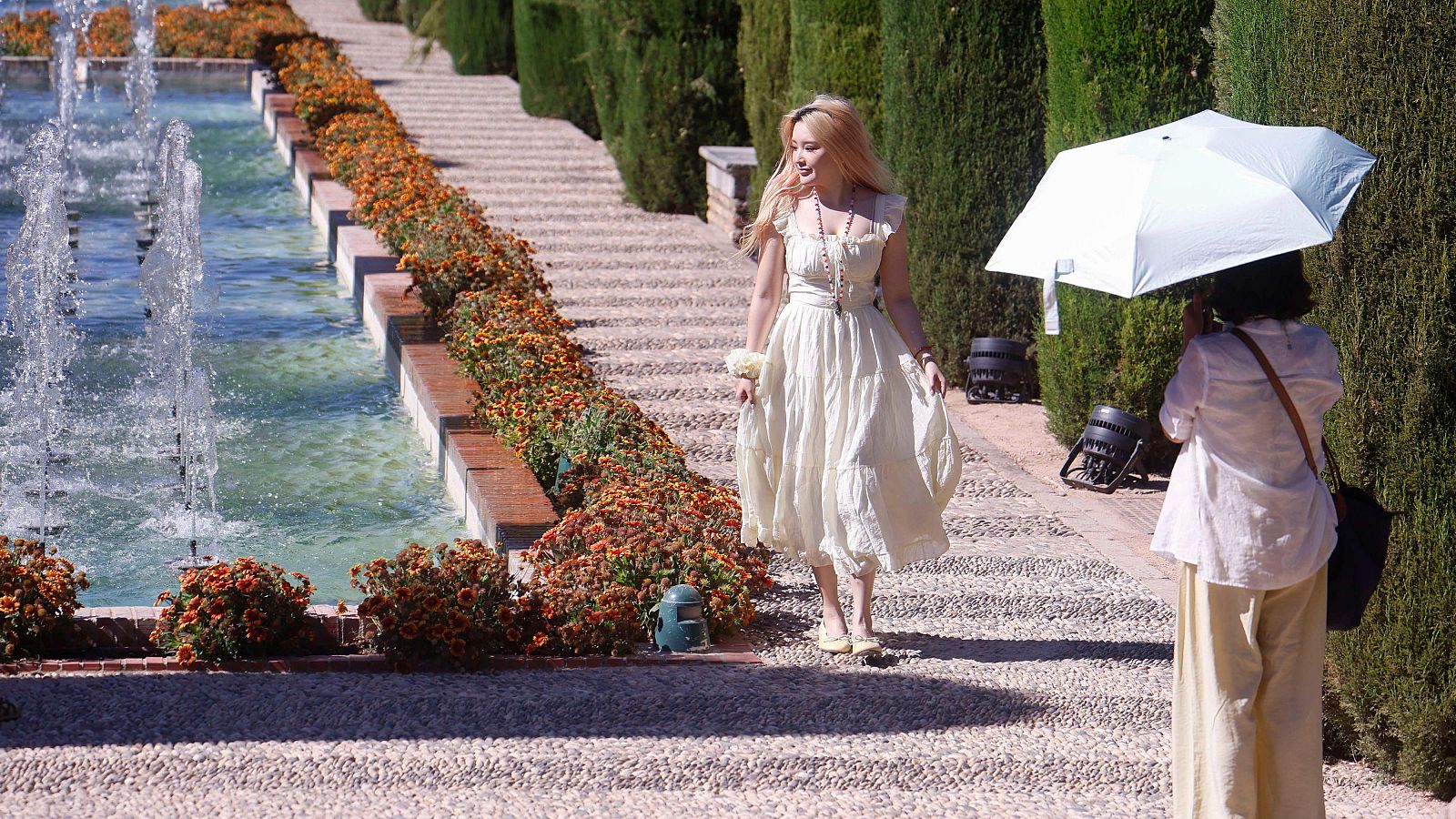 Turistas paseando con paraguas por las fuentes jardines del Alcázar de Córdoba para sofocar el intenso calor con temperaturas que llegan a los 38 grados
