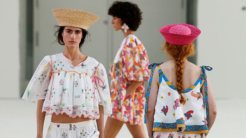 Modelos lucen coloridos diseños de Celia B en la Mercedes-Benz Fashion Week Madrid, con sombreros de paja como accesorio clave. Estampados de naturaleza y formas abstractas en tonos vivos.