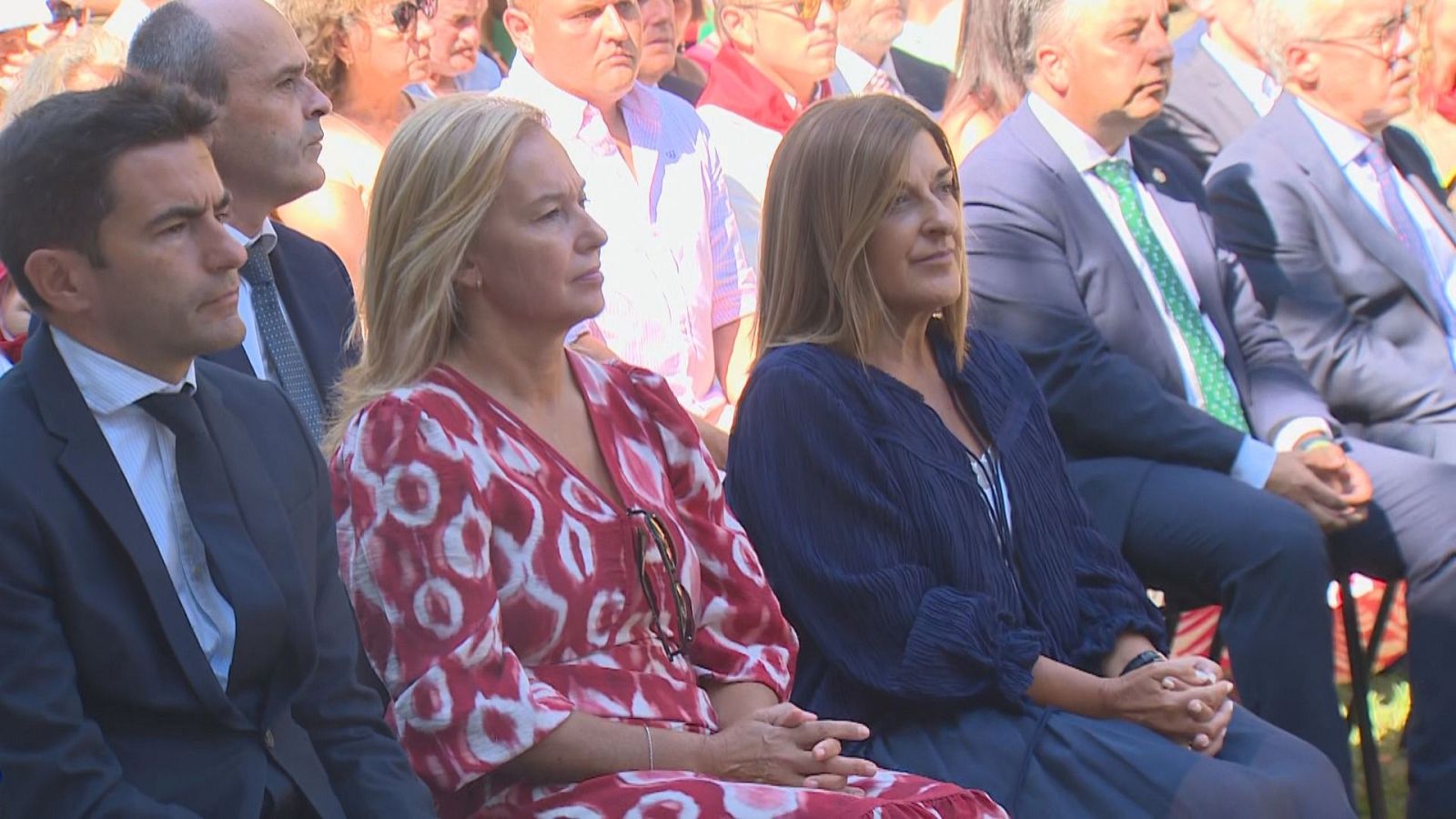 Pedro Casares, María José González Revuelta y María José Sáenz de Buruaga, destacadas políticas de Cantabria, asisten a un evento al aire libre, mostrando atención y seriedad.