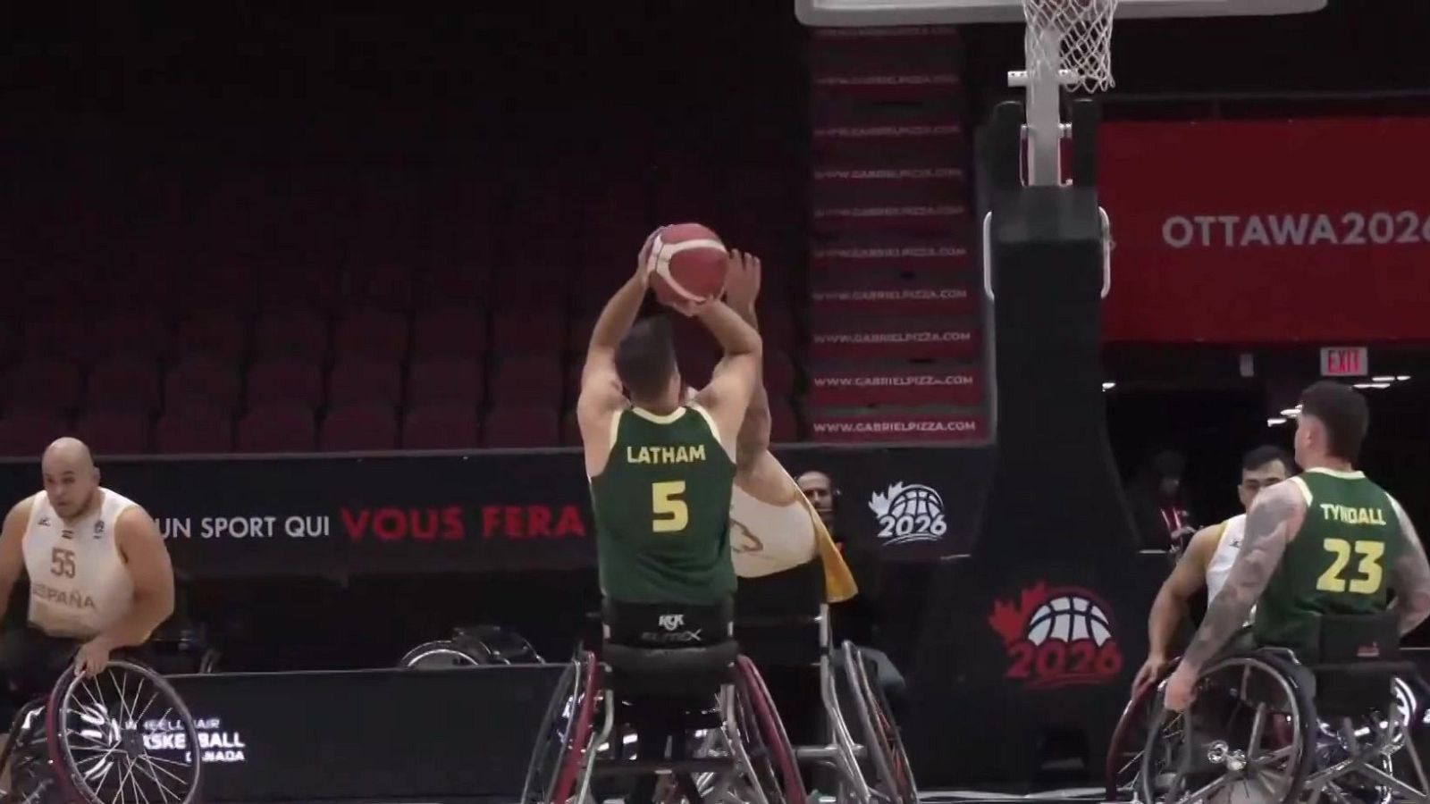 Jugador con camiseta "LATHAM 5" lanza balón rojo y blanco en partido de baloncesto en silla de ruedas. "OTTAWA 2026" y "BASKETBALL CANADA" visibles.