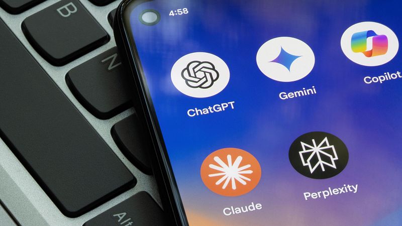 Primer plano de un smartphone con apps de IA (ChatGPT, Gemini, Copilot, Claude, Perplexity) sobre un teclado negro. Hora: 4:58.