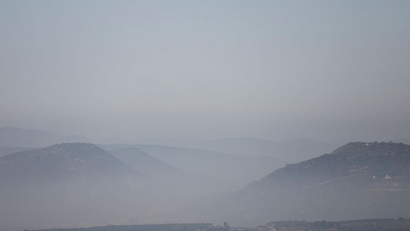 Paisaje montañoso brumoso con colinas en primer plano y montañas difuminadas al fondo. Atmósfera serena y melancólica con tonos apagados.