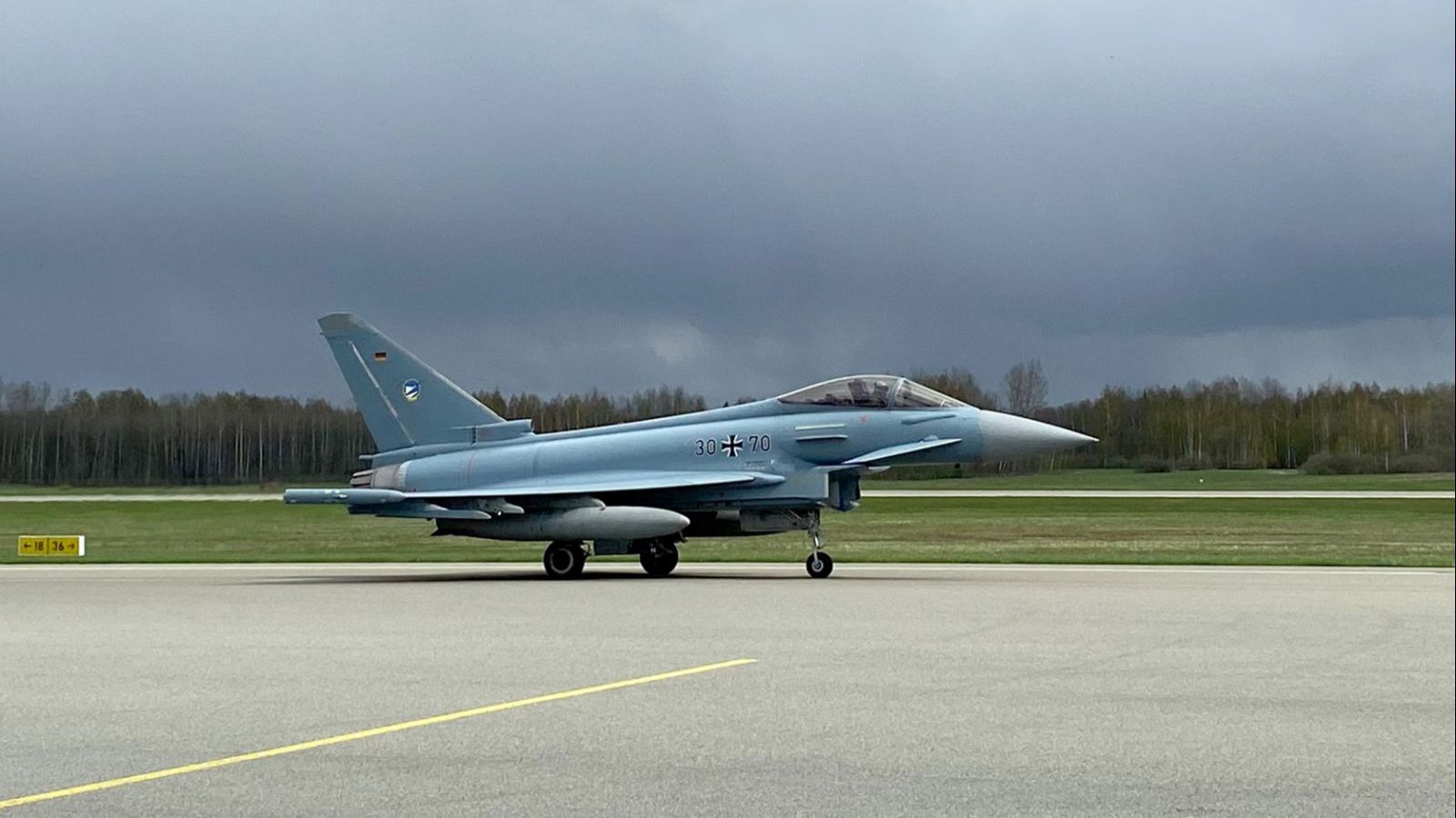 Eurofighter Typhoon de la Luftwaffe alemana, con código "30+70", en una pista de base aérea bajo cielo nublado. Se aprecian la bandera alemana y emblema de la Luftwaffe.
