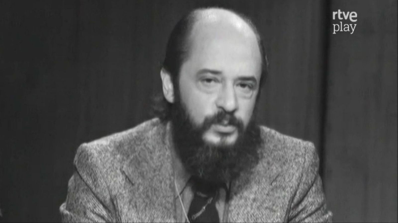 Retrato en blanco y negro de Fernando Jiménez del Oso, psiquiatra y parapsicólogo español, con barba y bigote oscuros, chaqueta de tweed y mirada seria. Logo 'rtve play' en la esquina superior derecha.