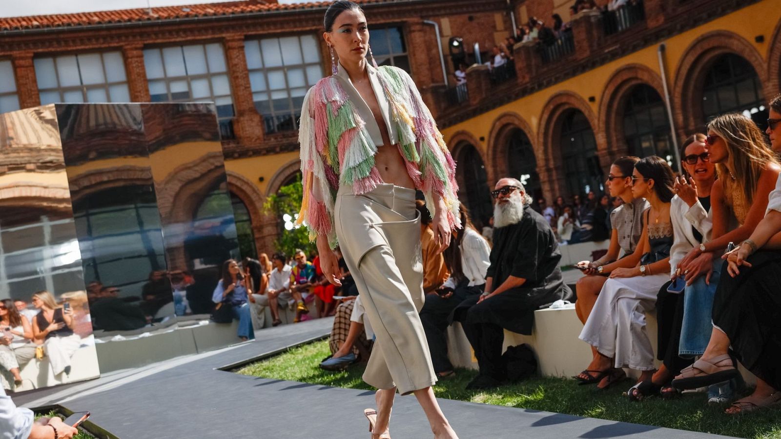 Modelo con chaqueta de flecos y pantalones asimétricos en la Mercedes-Benz Fashion Week Madrid. Boris Izaguirre presente en el evento.