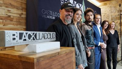 Personas posan en el photocall de "Blacklladolid 2026" en el Castillo de Valladolid. Se distingue un objeto conmemorativo con el nombre "MAR�A DUE�AS".