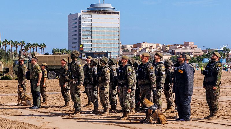 Militares españoles con perros de trabajo y un camión militar frente a un edificio moderno con el logo de McDonald's en Melilla.