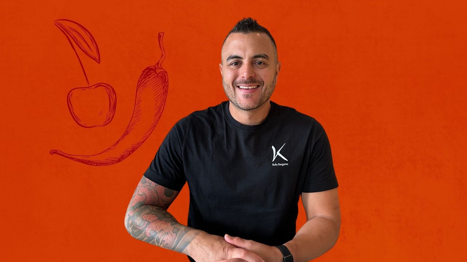 Chef Kike Bergara sonr�e con camiseta negra y logo "Kike Bergara". Fondo naranja con dibujos de cereza y guindilla.