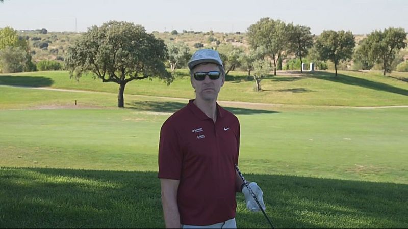 Pau Gasol, exjugador de baloncesto, en un campo de golf, con polo granate, gorra gris, gafas de sol y palo de golf.