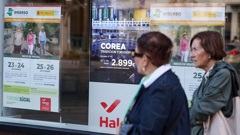 Mujeres observan carteles de viajes del Imserso y a Corea. Se detallan fechas de venta y destinos.