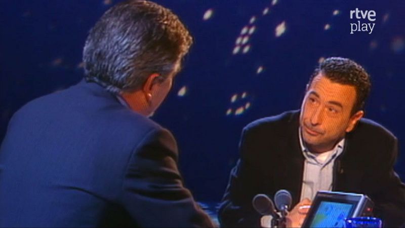 Pedro Ruiz y Jose Luis Garci en un plat� de "rtve play". Ruiz, de frente, con manos entrelazadas y micr�fonos delante. Garci, de espaldas, de perfil, con cabello canoso.