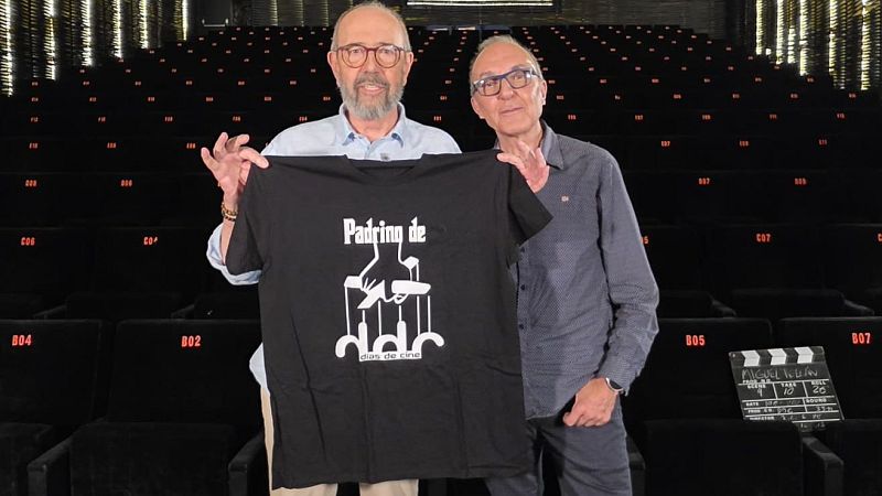 Miguel Rellán y otro hombre en un auditorio vacío, con una claqueta de "Días de cine" y una camiseta de "Padrino de" que hace referencia a "El Padrino".