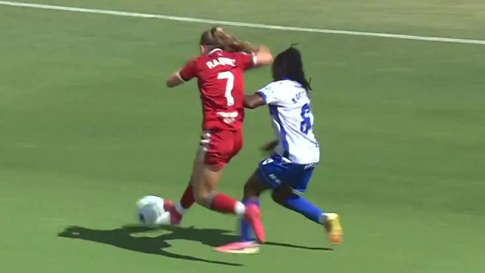 Jugadoras de fútbol femenino en acción: la número 7 con uniforme rojo y la número 8 con uniforme azul y blanco compiten por el balón en un campo de césped.
