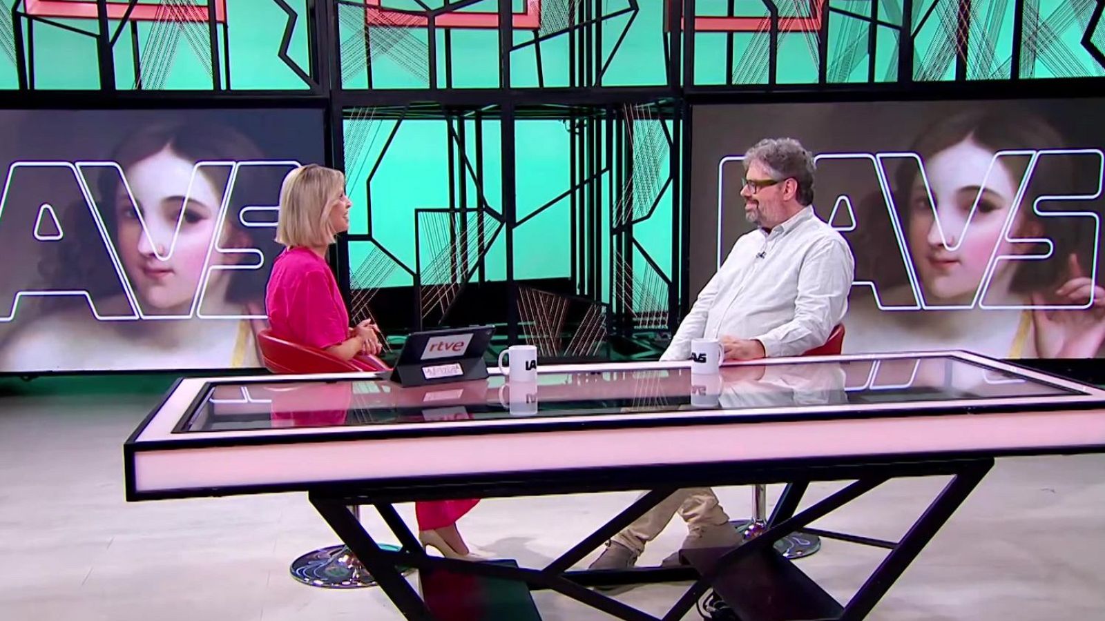 Elisabeth Pérez y Salvador Gómez Valdés en el estudio de "La Aventura del Saber" de RTVE, con pantallas mostrando el título del programa y un rostro artístico.