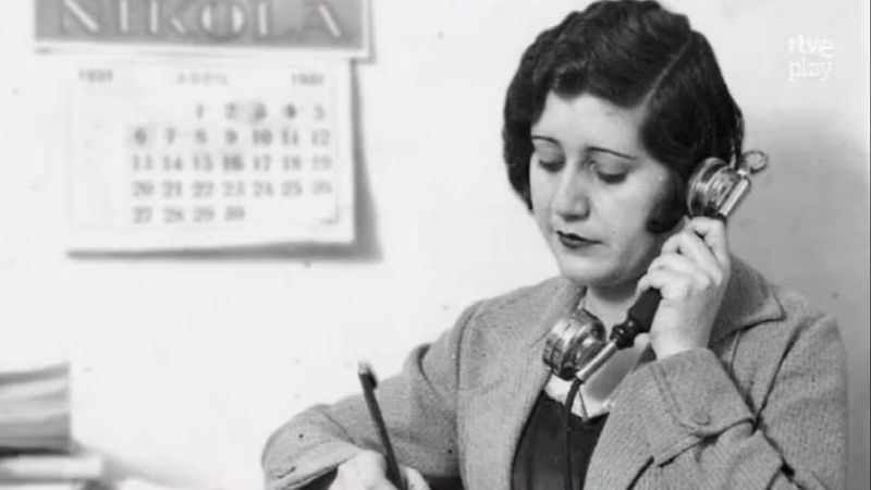 Josefina Carabias, periodista, en un primer plano de medio cuerpo, con un teléfono antiguo y bolígrafo, tomando notas. Calendario de abril de 1931 al fondo. Marca de agua 'rtve play'.