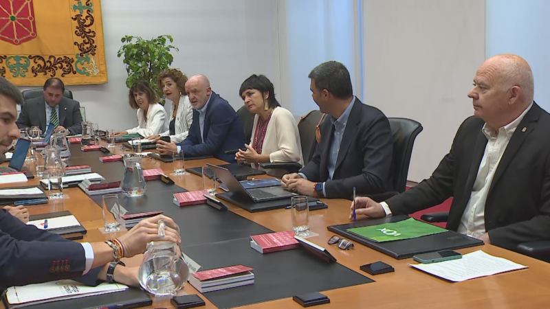 Reunión formal de la Mesa y Junta del Parlamento. Carlos Verdejo, presidente de VOX Ceuta, presente. Tapiz con el Escudo de Navarra al fondo.